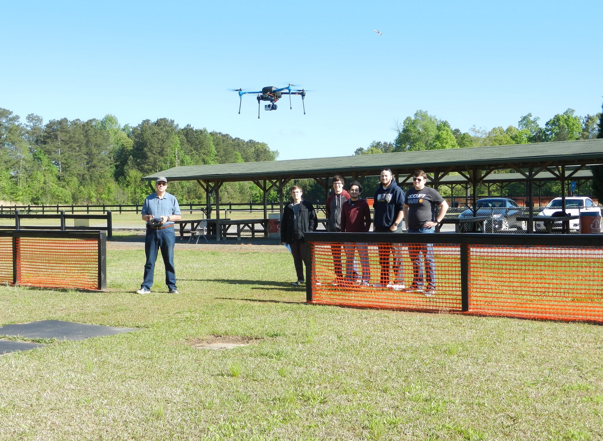 A flying quadcopter being observed by a group of people