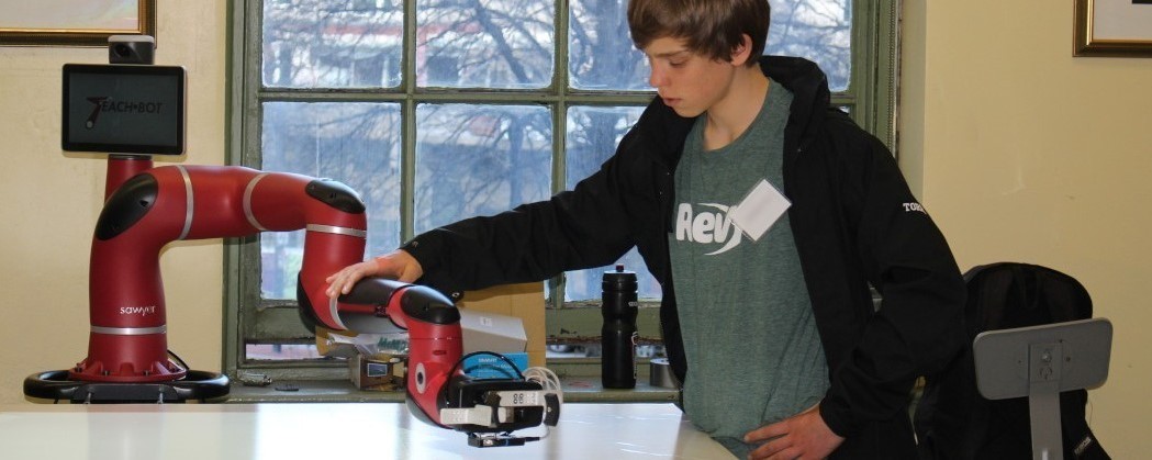 A student interacting with a collaborative manufacturing robot